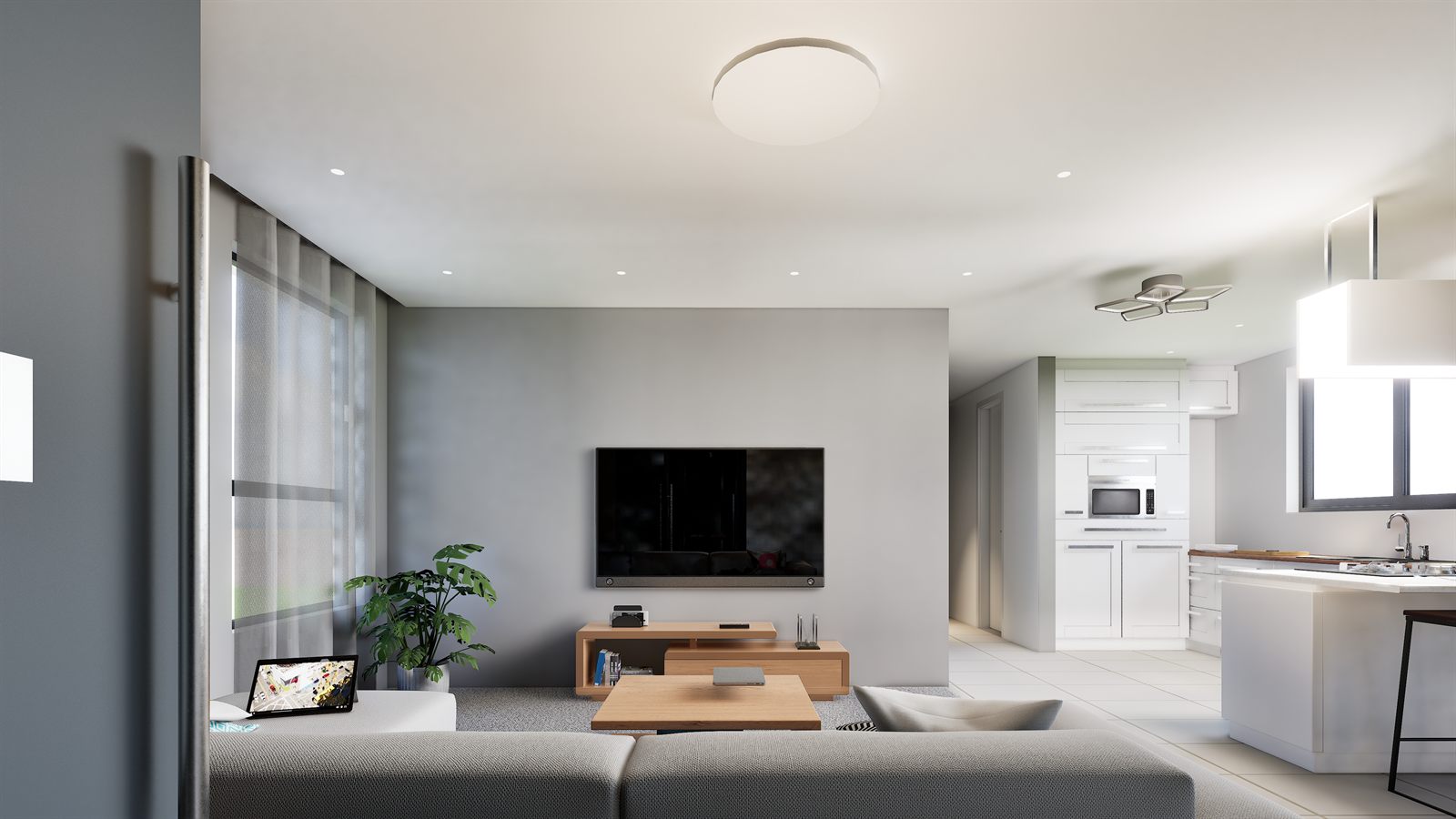 The living area: a grey sofa and timber coffee tables facing a wall-hung television on a grey feature wall, a curtained window to the left, and the kitchen open through to the right.